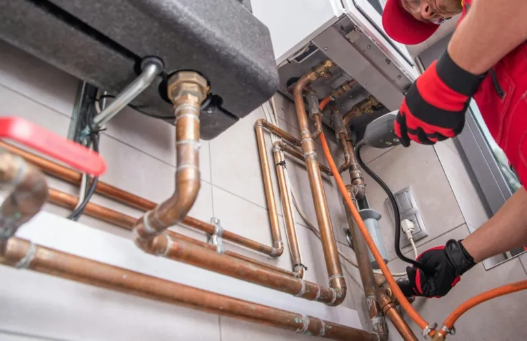 Plumber working on copper pipes beneath a sink