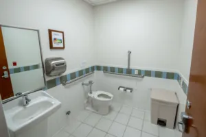 Accessible commercial restroom with sink, toilet, and support rails