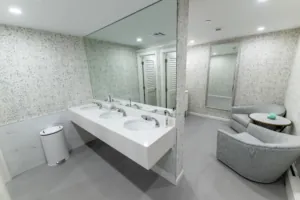 Restroom sink counter with mirrors and lounge chair