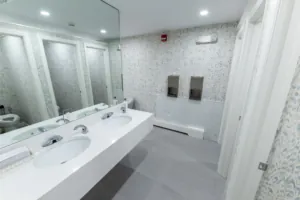 Long restroom sink counter beneath a wall mirror