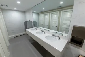 Double vanity with wall-mounted dispensers in a renovated restroom