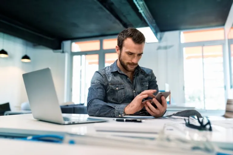 Man reviewing a smartphone at an office desk