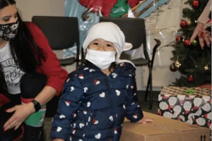 Child opening a holiday gift with an adult